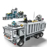 A gray toy truck with a building on top and a separate building behind it.