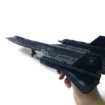 A hand holds a black toy airplane with "U.S. AIR FORCE" and "SR-71 Blackbird" printed on it.