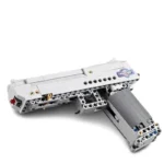 A gray toy gun made of interlocking blocks is presented.