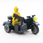 A yellow figure holds a black gun while riding a dark motorcycle with a sidecar.