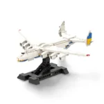 A white toy airplane with blue and yellow accents is displayed on a black stand.