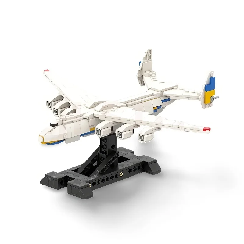 A white toy airplane with blue and yellow accents is displayed on a black stand.