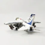 White and gray toy airplane with navy markings and weapons attached under the wings.