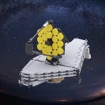 A toy model of a telescope with a large, segmented yellow mirror and white support structure.