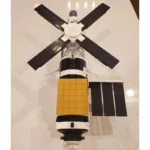A toy satellite with black and yellow panels and four black solar panels.