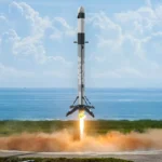 A toy rocket with a gray and white pattern is launching with flames at the base.