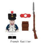 A toy figure with a black hat, blue jacket, and white pants is next to a brown rifle, a red connector, and a brown bag.