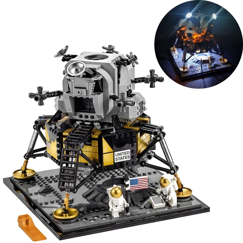 A toy lunar lander with two astronaut figures and an American flag on a gray base.
