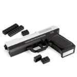A toy gun made of black and silver blocks with several loose blocks nearby.