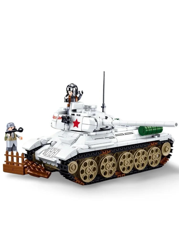 A white toy tank with a red star and two figures, one standing near a brown fence.