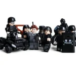 A group of toy figures includes several figures in black uniforms and one in a gray suit, some holding a shield and one on a vehicle.