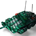 A green toy tank with black treads, two antennas, and a red object on top.