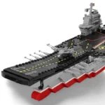 A toy aircraft carrier with a black deck, gray and red hull, and several small gray planes.