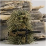 A toy figure wearing a ghillie suit holds a rifle.