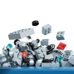 A pile of gray, red, and black toy bricks with some wheels and translucent blue pieces.