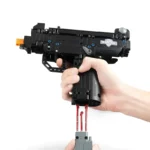 A hand holds a black toy gun with red rods extending from the bottom.