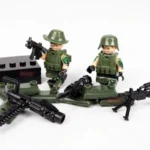 Two toy figures in green military outfits are holding weapons, with additional toy weapons nearby.